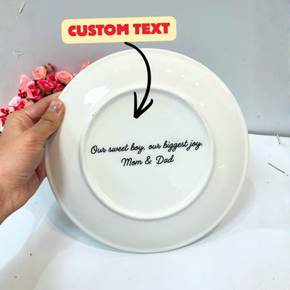 White plate with personalized text held by a hand, with flowers in the background.